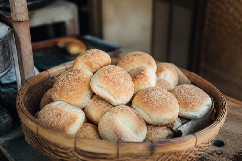 A basket of freshly baked sourdough pandesal dusted with breadcrumbs